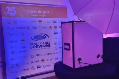 Borne photo avec éclairage, clavier et imprimante posée sur des tables noires dans un espace intérieur.