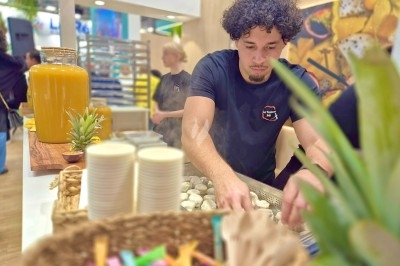 Un homme prépare des aliments sur un stand culinaire avec des boissons et des accessoires en arrière-plan.