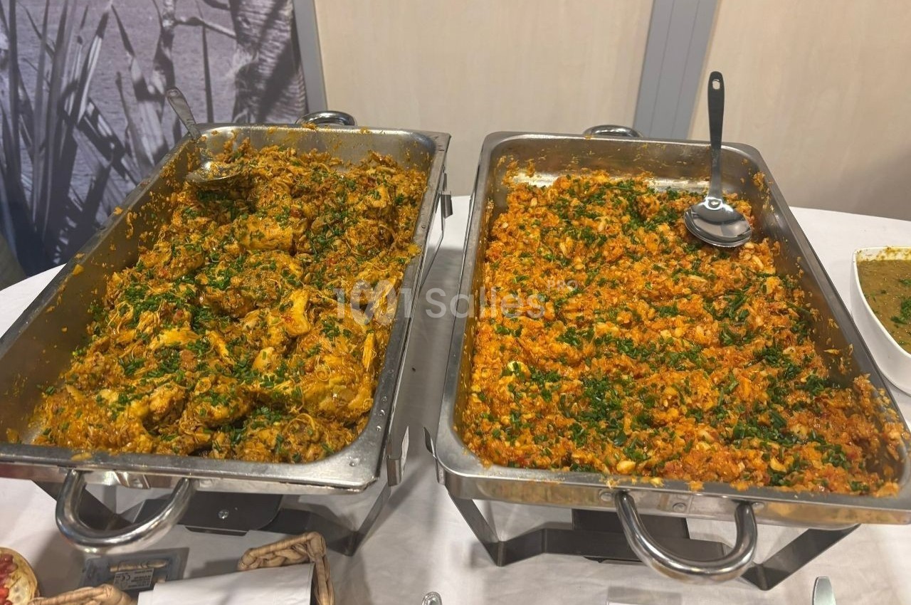 Deux plats en inox contenant des préparations épicées garnies de persil, présentés sur une table de buffet.
