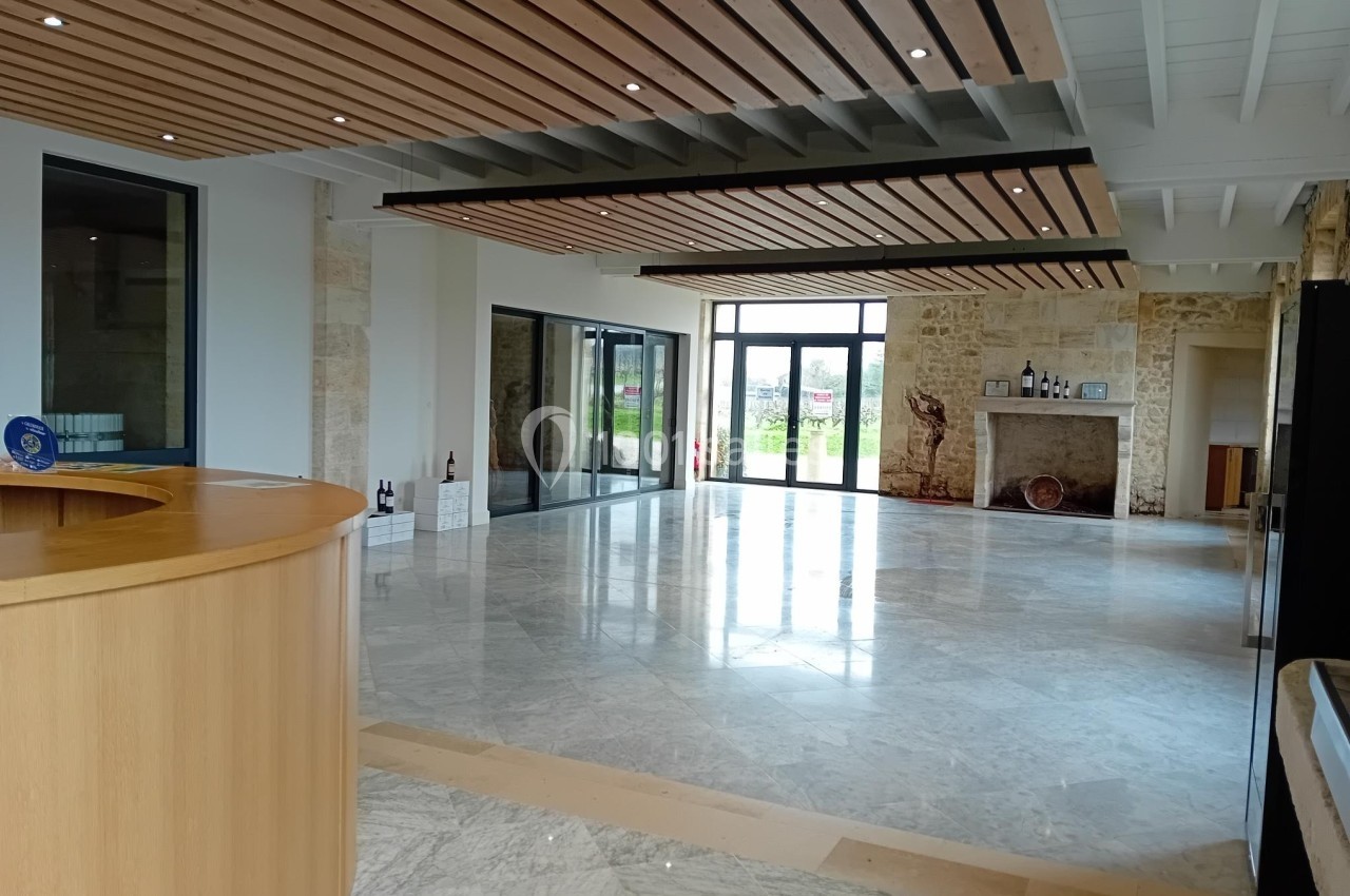 Salle lumineuse avec sol en marbre, comptoir en bois, murs en pierre et grandes baies vitrées donnant sur l'extérieur.