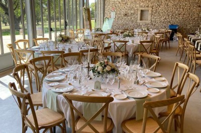Miniature Mas Adamon Location #4 Table dressée en extérieur avec nappes blanches, verres et décorations florales, entourée de chaises en bois.