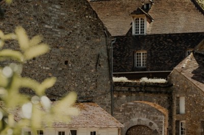 Salle de réception décorée avec des guirlandes lumineuses, tables rondes dressées et chaises blanches.