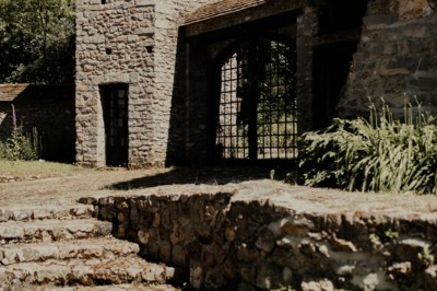 Salle de réception décorée avec des guirlandes lumineuses, tables rondes dressées et chaises blanches.