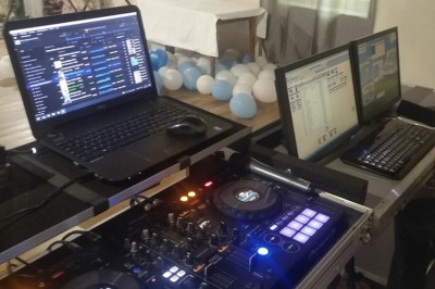 Salle de réception décorée avec des guirlandes lumineuses, tables rondes dressées et chaises blanches.