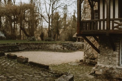 Salle de réception décorée avec des guirlandes lumineuses, tables rondes dressées et chaises blanches.