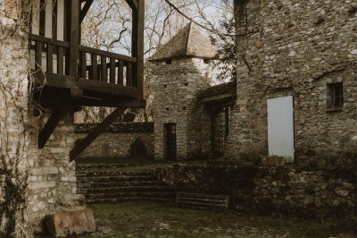 Salle de réception décorée avec des guirlandes lumineuses, tables rondes dressées et chaises blanches.