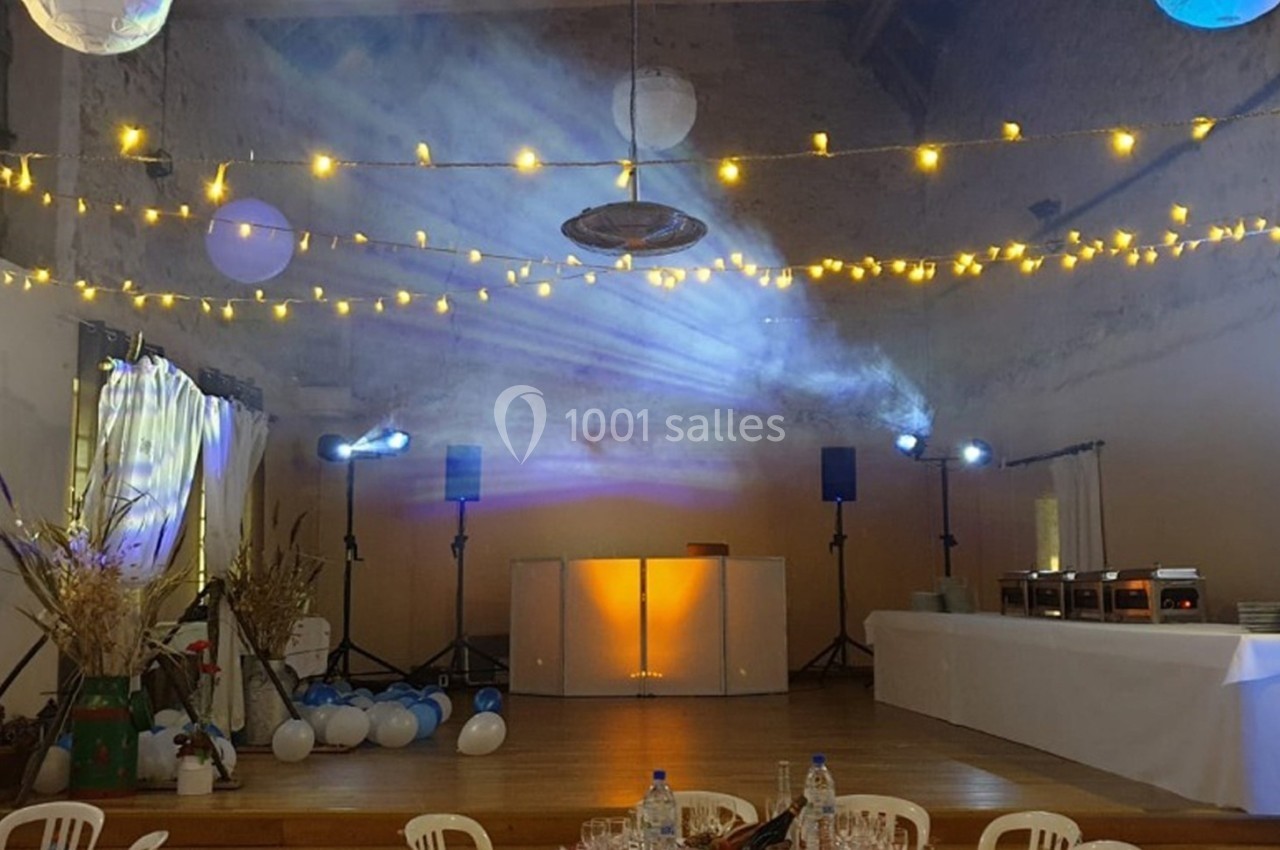 Salle décorée pour un événement avec guirlandes lumineuses, projecteurs colorés et table de buffet alignée à droite.