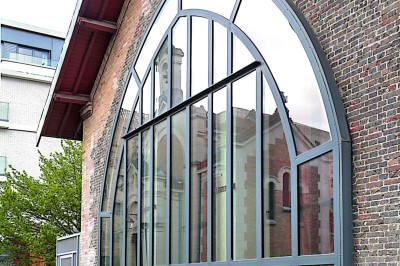 Buste masculin noir sans tête, orné de motifs colorés, exposé devant un rideau rouge et un piano en arrière-plan.