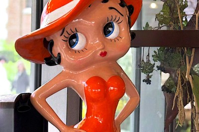 Buste masculin noir sans tête, orné de motifs colorés, exposé devant un rideau rouge et un piano en arrière-plan.