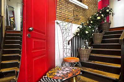 Buste masculin noir sans tête, orné de motifs colorés, exposé devant un rideau rouge et un piano en arrière-plan.