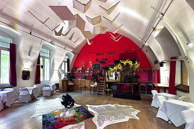 Buste masculin noir sans tête, orné de motifs colorés, exposé devant un rideau rouge et un piano en arrière-plan.