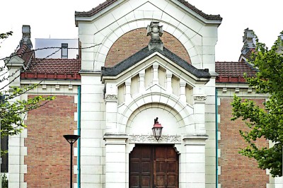 Buste masculin noir sans tête, orné de motifs colorés, exposé devant un rideau rouge et un piano en arrière-plan.