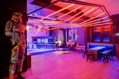 Escalier intérieur avec murs sombres décorés de néons roses et motifs géométriques, éclairage tamisé.