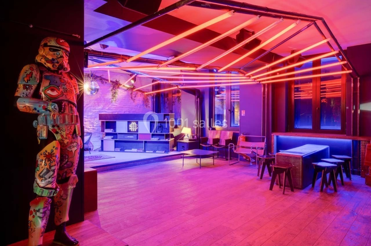 Salle moderne avec éclairage néon rose, mobilier minimaliste et statue décorative colorée dans un coin.