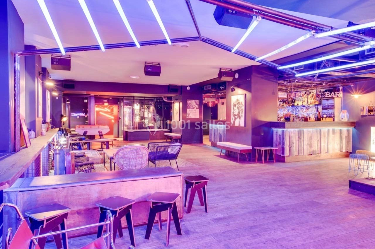 Salle de bar moderne avec éclairage néon violet, mobilier en bois et métal, ambiance conviviale.