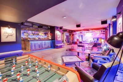Escalier intérieur avec murs sombres décorés de néons roses et motifs géométriques, éclairage tamisé.