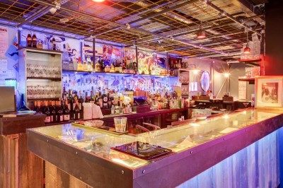 Escalier intérieur avec murs sombres décorés de néons roses et motifs géométriques, éclairage tamisé.