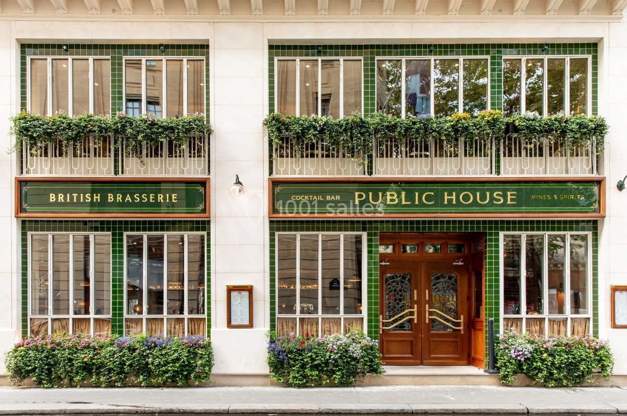 Façade d'un pub avec enseignes ’British Brasserie’ et ’Public House’, décorée de plantes et carreaux verts.