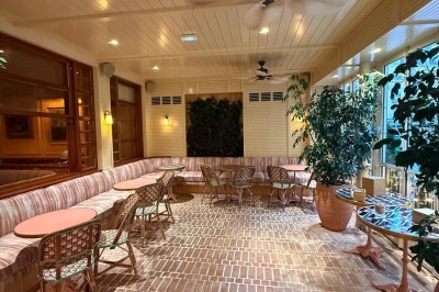 Salle avec tables et chaises en bois, banquettes rouges, murs à motif écossais et éclairage tamisé.
