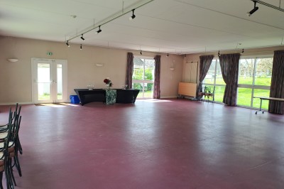 Pelouse verte entourée de bâtiments en briques et crépi, avec arbres et allée en béton sous un ciel dégagé.