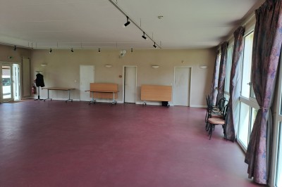 Pelouse verte entourée de bâtiments en briques et crépi, avec arbres et allée en béton sous un ciel dégagé.