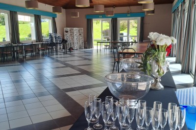 Pelouse verte entourée de bâtiments en briques et crépi, avec arbres et allée en béton sous un ciel dégagé.