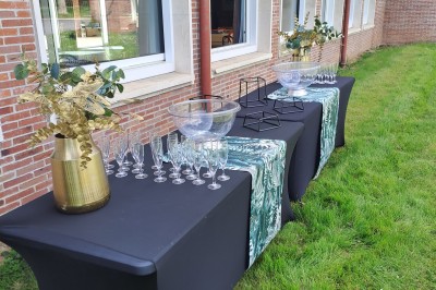 Pelouse verte entourée de bâtiments en briques et crépi, avec arbres et allée en béton sous un ciel dégagé.