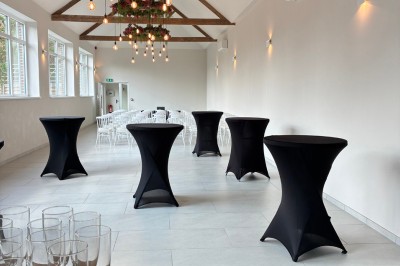 Salle lumineuse avec des rangées de chaises blanches alignées, plafond avec poutres apparentes et décor floral suspendu.