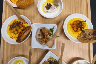 Plateau en bois avec plusieurs petites assiettes contenant des amuse-bouches variés et des cuillères en bois.