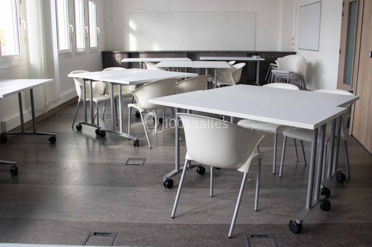Location salle Mont-de-Marsan (Landes) - Cci des Landes #7 Salle de classe lumineuse avec des tables blanches sur roulettes et des chaises, entourée de fenêtres et d'un tableau blanc.