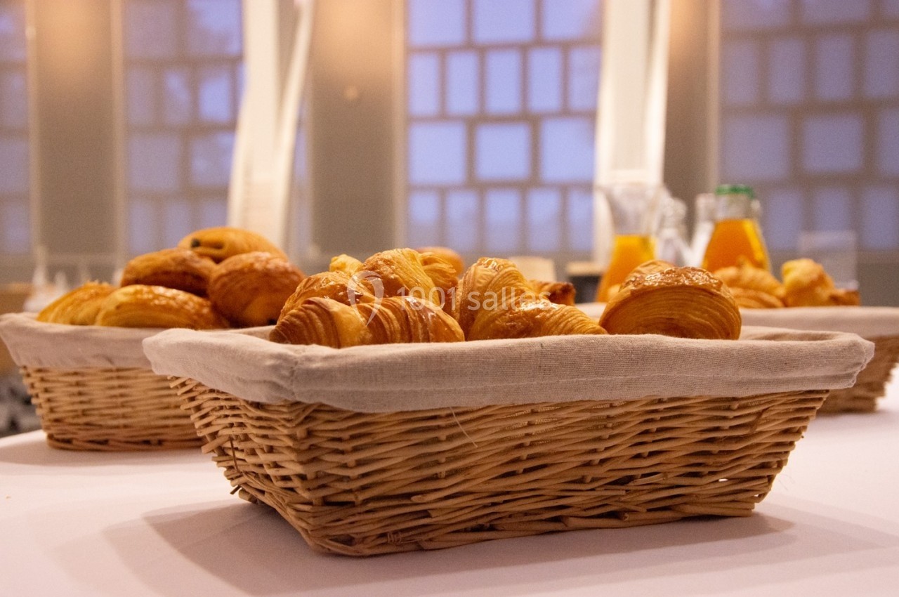 Location salle Mont-de-Marsan (Landes) - Cci des Landes #9 Paniers en osier remplis de viennoiseries sur une table, avec des carafes de jus d'orange en arrière-plan.