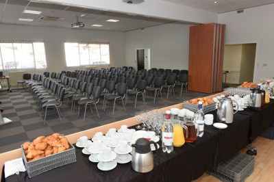 Paniers de viennoiseries avec jus d'orange et cafetière en arrière-plan dans une salle lumineuse.