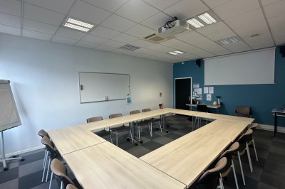 Paniers de viennoiseries avec jus d'orange et cafetière en arrière-plan dans une salle lumineuse.
