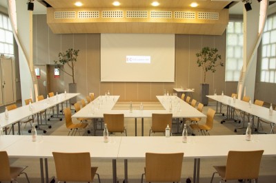 Paniers de viennoiseries avec jus d'orange et cafetière en arrière-plan dans une salle lumineuse.