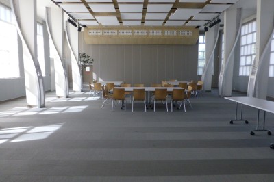 Paniers de viennoiseries avec jus d'orange et cafetière en arrière-plan dans une salle lumineuse.