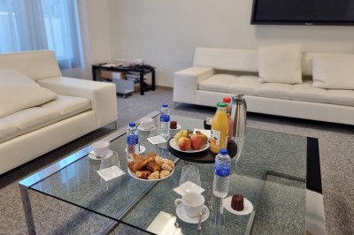 Paniers de viennoiseries avec jus d'orange et cafetière en arrière-plan dans une salle lumineuse.