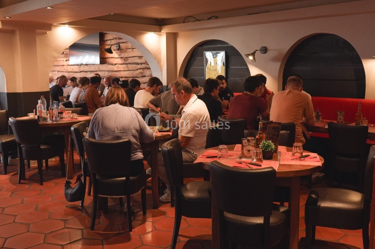 Location salle Villeneuve-Loubet (Alpes-Maritimes) - Pizzatti Villeneuve Loubet #8 Des personnes dînent dans un restaurant à l'ambiance chaleureuse, assises à des tables rondes avec nappes rouges.