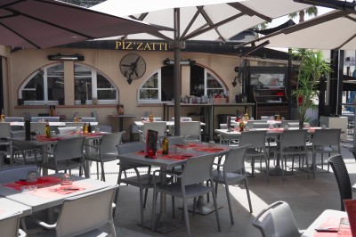 Miniature Location salle Villeneuve-Loubet (Alpes-Maritimes) - Pizzatti Villeneuve Loubet #5 Des personnes dînent dans un restaurant à l'ambiance chaleureuse, assises à des tables rondes avec nappes rouges.