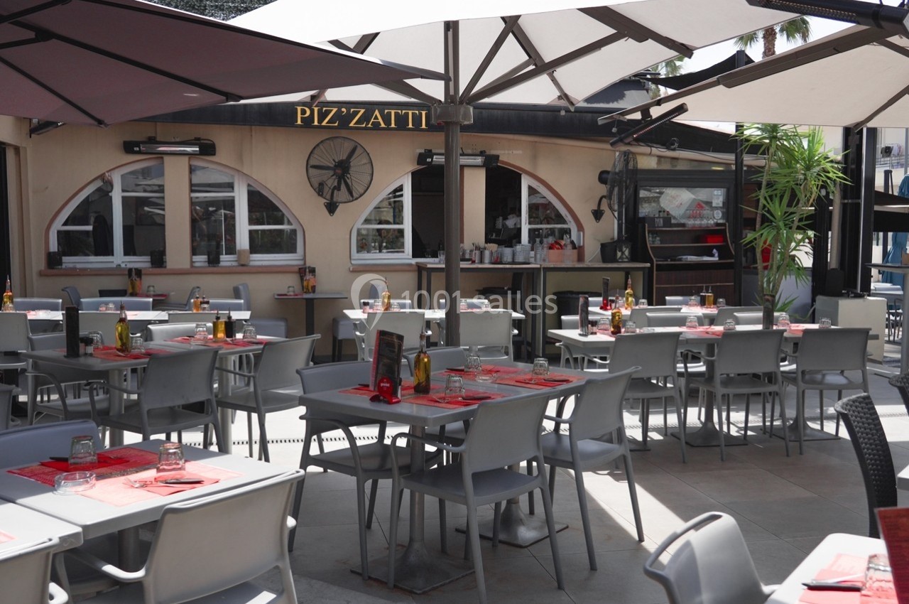 Location salle Villeneuve-Loubet (Alpes-Maritimes) - Pizzatti Villeneuve Loubet #5 Terrasse d'un restaurant avec des tables dressées, chaises grises et parasols, devant une façade beige avec des fenêtres…