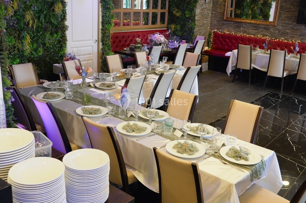 Salle de réception décorée avec des tables dressées, nappes blanches, assiettes et chaises beige, ambiance élégante.