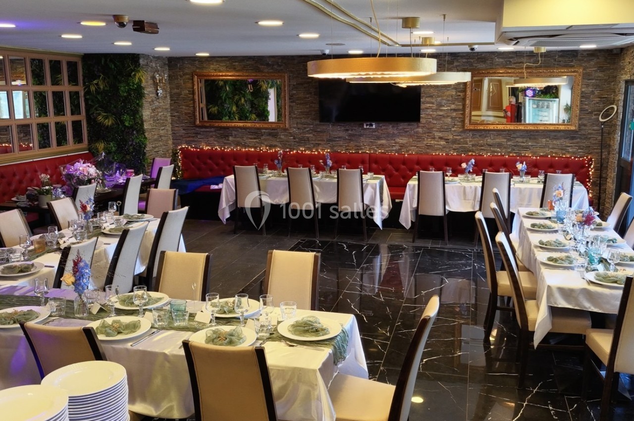 Salle de réception élégamment décorée avec tables dressées, nappes blanches et chaises autour, prête pour un événement.
