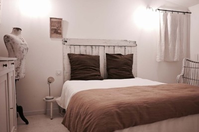 Quatre lits simples alignés dans une chambre lumineuse avec murs blancs, décor minimaliste et poutres apparentes.