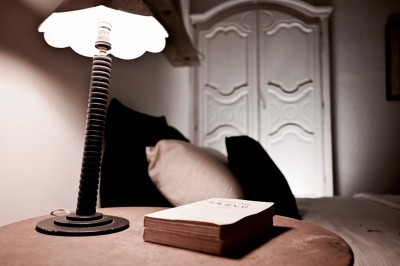 Quatre lits simples alignés dans une chambre lumineuse avec murs blancs, décor minimaliste et poutres apparentes.
