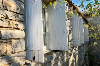 Quatre lits simples alignés dans une chambre lumineuse avec murs blancs, décor minimaliste et poutres apparentes.