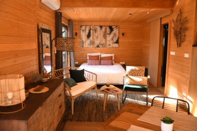 Tente de style yourte avec terrasse en bois, entourée d'arbres dans un cadre naturel.