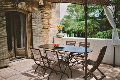 Tente de style yourte avec terrasse en bois, entourée d'arbres dans un cadre naturel.