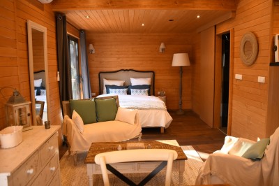 Tente de style yourte avec terrasse en bois, entourée d'arbres dans un cadre naturel.