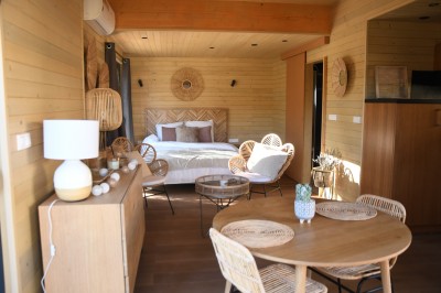 Tente de style yourte avec terrasse en bois, entourée d'arbres dans un cadre naturel.
