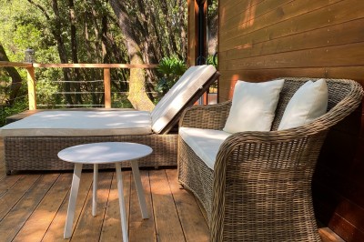 Tente de style yourte avec terrasse en bois, entourée d'arbres dans un cadre naturel.