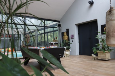 Mur en briques décoré de miroirs et d'une porte en bois sculpté, avec des canapés colorés en premier plan.